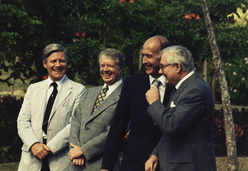 Die vier Regierungschefs stehen in Anzug und Krawatte nebeneinander und lachen.
