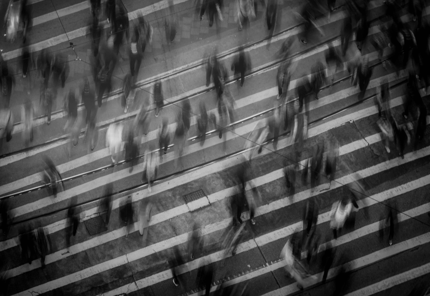 Viele Menschen überqueren eine Straße. Die Schwarz-Weiß-Fotografie ist verwischt.