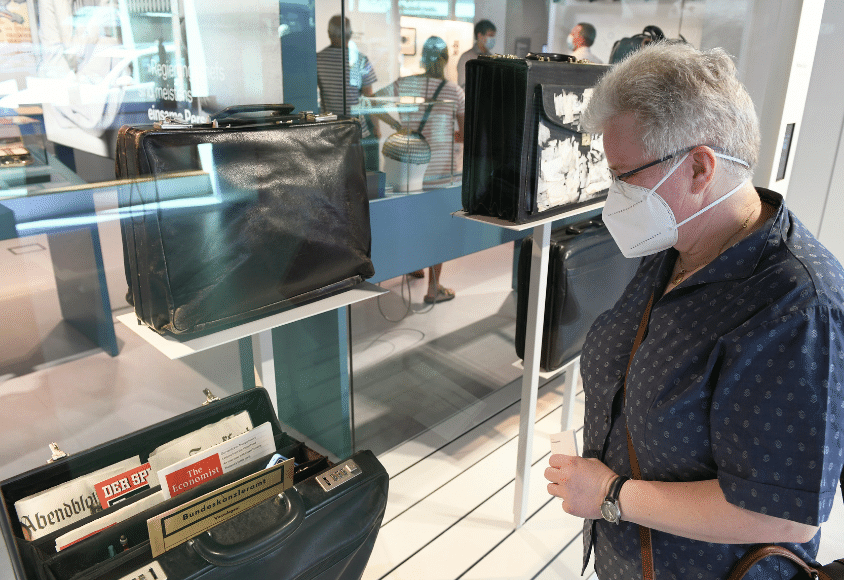 Eine Frau betrachtet Schmidts Aktentaschen, die in der Ausstellung „Schmidt!Demokratie leben“ ausgestellt sind.