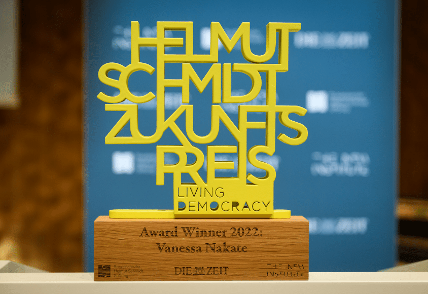 Nahaufnahme des Awards. Er besteht aus dem gelben Schriftzug: Helmut Schmidt Zukunftspreis.