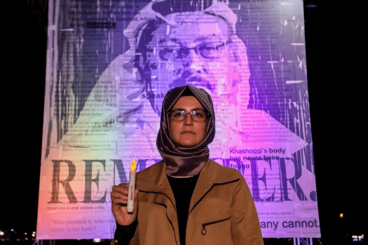 Hatice Cengiz steht mit einer Kerze in der Hand vor einem großen Plakat, das ihren Verlobten Jamal Khashoggi mit der Aufschrift „remember“ zeigt.