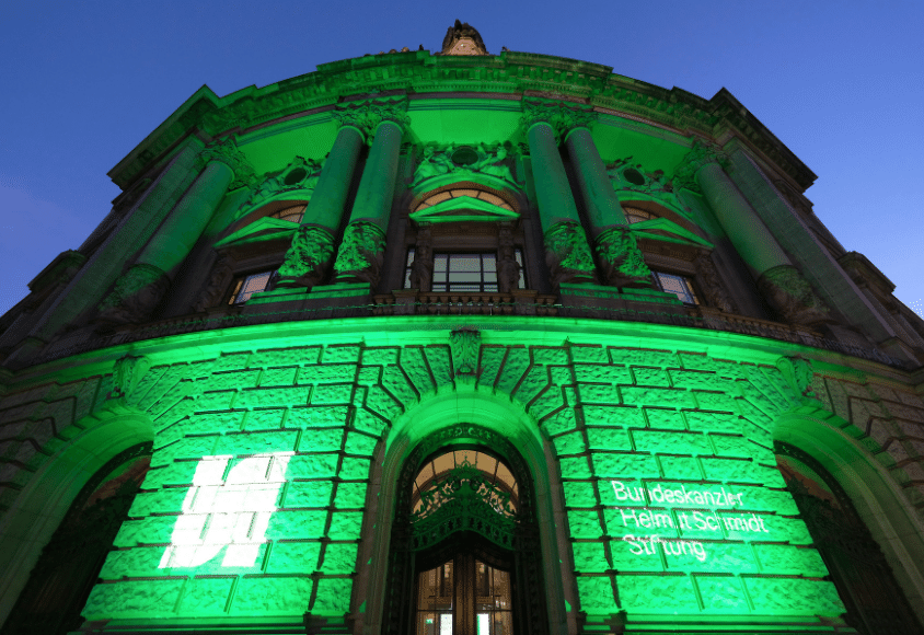 Nachtansicht des Museums für Kommunikation. Der wilhelminische Eckbau wird mit grünen Scheinwerfern angestrahlt.