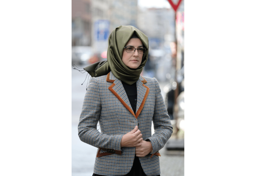 Hatice Cengiz in grünem Hidschab und kariertem Blazer auf der Straße. 
