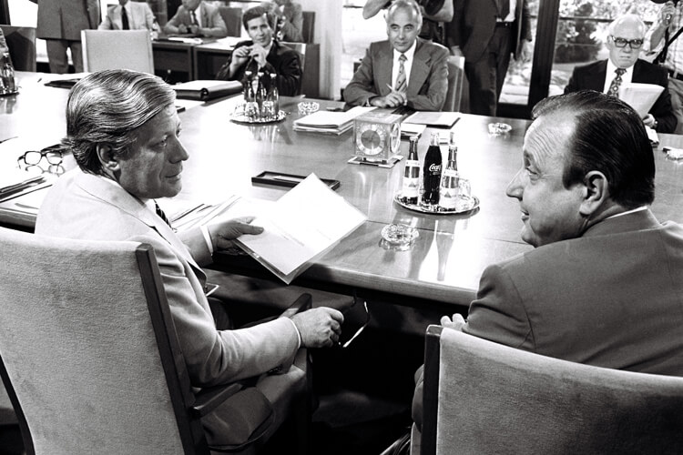 Franz Joseph Strauss und Helmut Schmidt unterhalten sich an einem Konferenztisch.