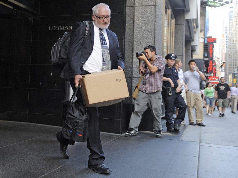 Man in a suit with a cardboard box in his hand on Wall Street, photographer and policewoman in the background