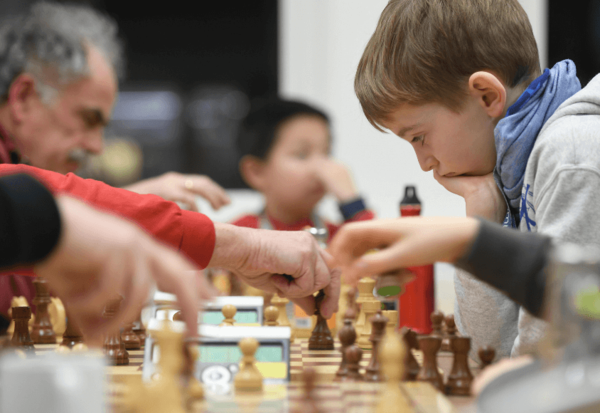 Junge und ältere Menschen spielen Schach.