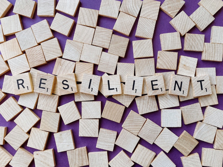 Holzklötze mit Buchstaben aneinandergereiht zum Wort "Resilient"