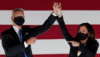 Joe Biden und Kamala Harris strecken Hände zusammen in Höhe, beide mit Atemschutzmasken, 
