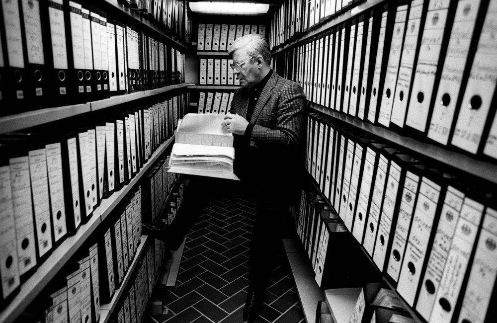 Helmut Schmidt with book in hand in archive with cupboards full of files