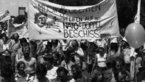 Black and white photo of crowd of demonstrators with large banner