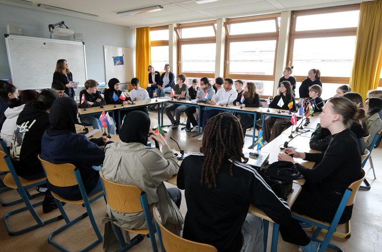 Colour photo: Young people sitting in a circle at tables playing the escape game Unlock Europe
