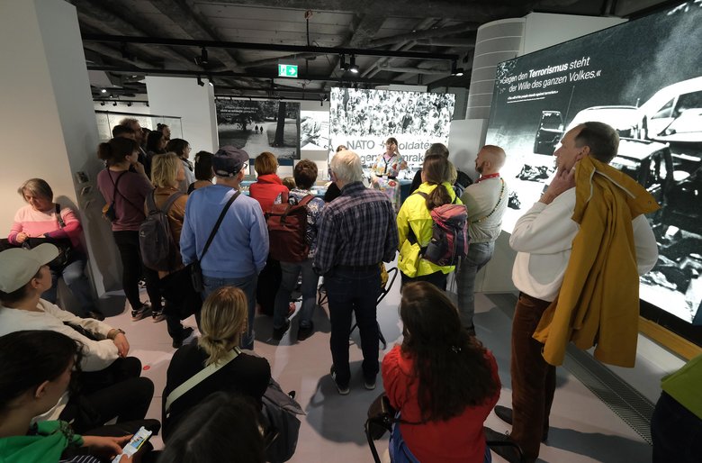 Colour photo: lots of people are standing in the exhibition.