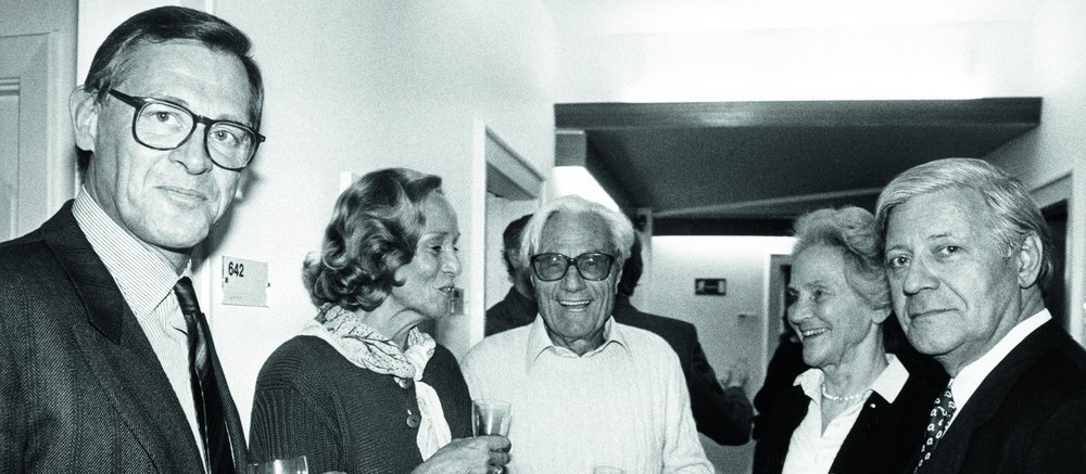 Schwarz-weiß Foto von drei Männern und zwei Frauen mit Sektgläsern in der Hand.