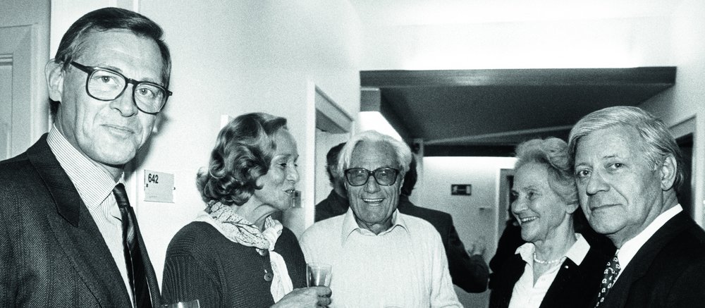 Black-and-white photo of three men and two women holding champagne glasses.