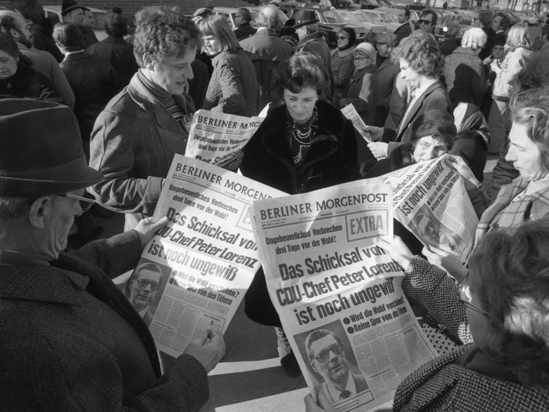 Black and white photo of several people reading the Berliner Morgenpost
