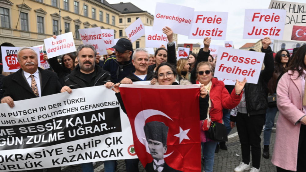 A group of demonstrators holding placards reading “Independent Judiciary” and “Freedom of the Press”, and a flag