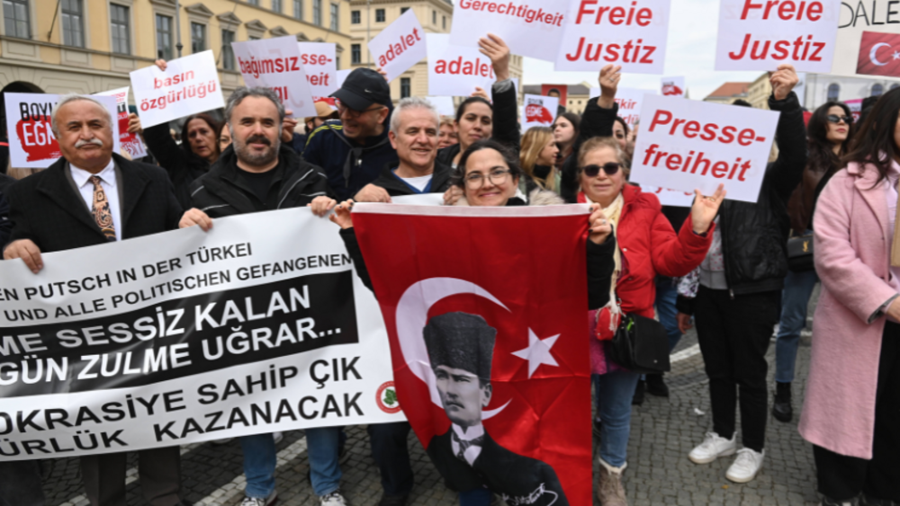 Gruppe von Demonstrierenden mit Plakaten "Freie Justiz" und "Pressefreiheit" und Flagge