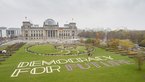 Teilnehmer des ersten Bürgerrates als lebendiges Kunstwerk in einer Spirale inszeniert auf der Wiese vor dem Reichstag. Auf dem Rasen neben ihnen liegt der Schriftzug "Democracy For Future".