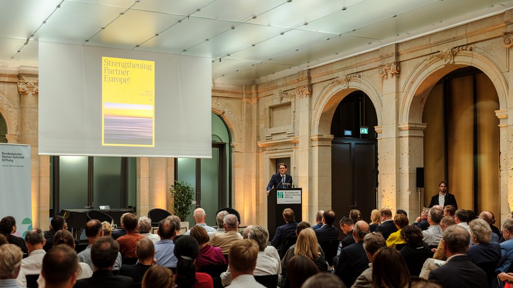 Colour photo: Meik Woyke is on stage presenting the magazine for the lecture “Strengthening Partner Europe!”
