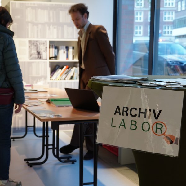Colour photo: Archive laboratory workshop. People are standing in front of a table.
