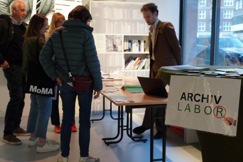 Colour photo: Archive laboratory workshop. People are standing in front of a table.