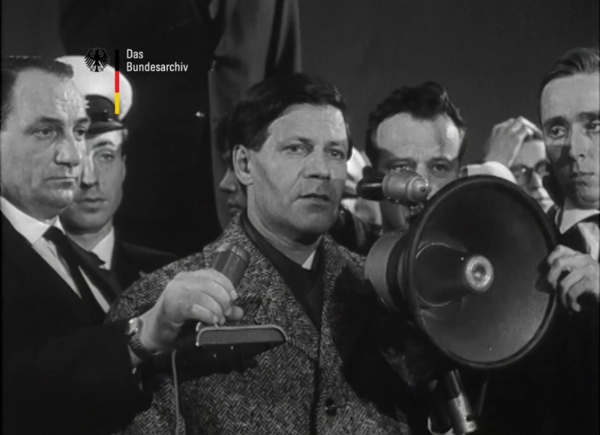 Mehrere Personen stehen mit Mikrophon und Megaphon um Helmut Schmidt, der eine Ansprache hält.