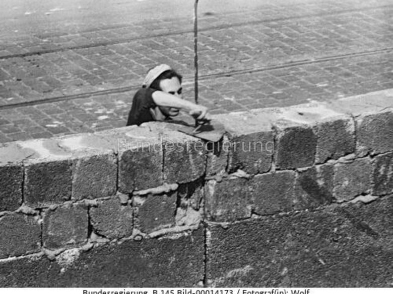 Black-and-white photograph of construction workers building a wall