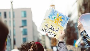 Poster with the inscription "We stand with Ukraine" above the heads of demonstrators