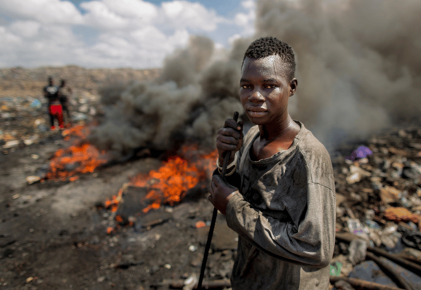Junger Mann auf der größten brennenden Elektroschrott-Deponie Afrikas.