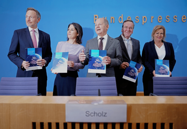 Christian Lindner, Annalena Baerbock, Olaf Scholz, Boris Pistorius und Nancy Faeser stehen vor einer blauen Wand und halten blaue Hefte ein den Händen.