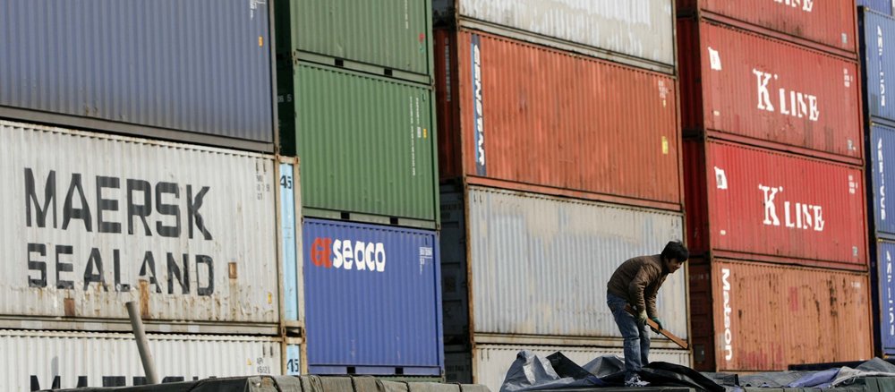 A worker standing in front of containers at a storage depot