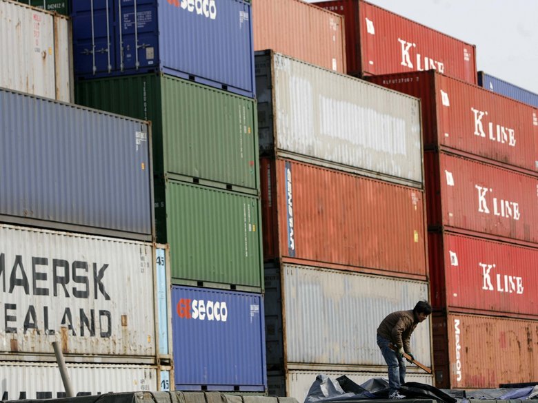 A worker standing in front of containers at a storage depot
