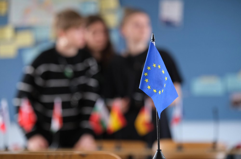 EU flag in the foreground and pupils blurred in the background