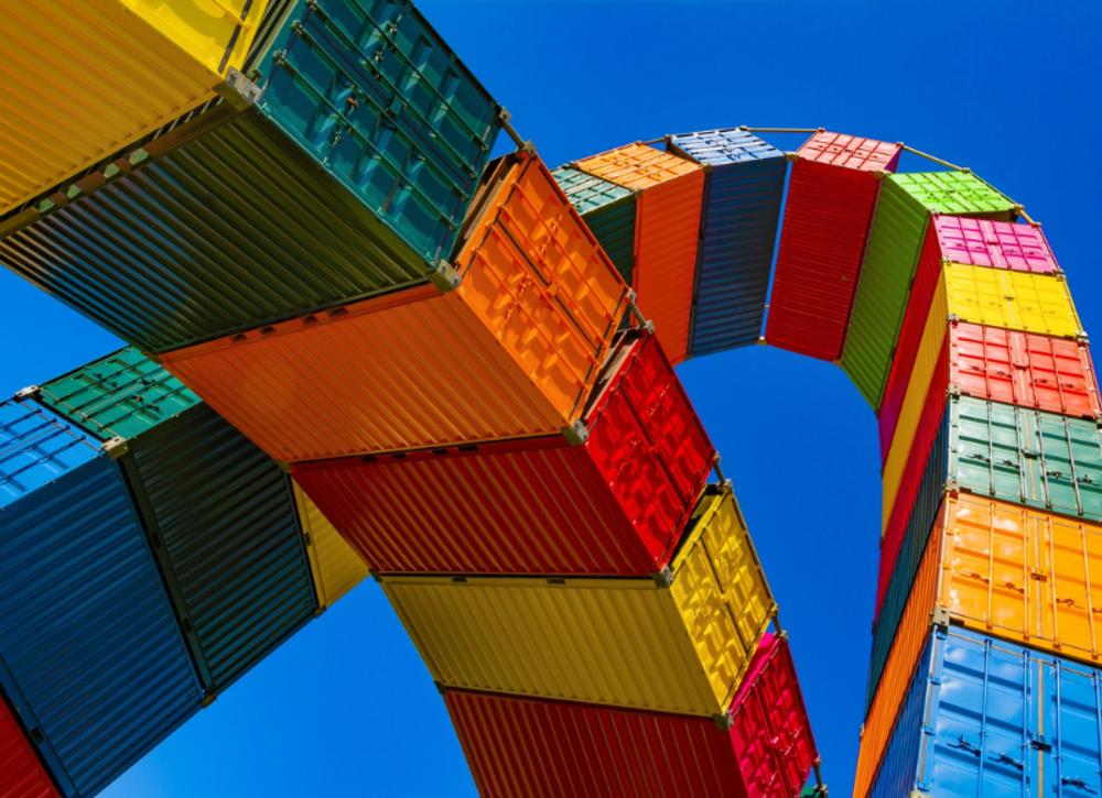 Colourful containers are stacked on top of each other and the perspective is from below.