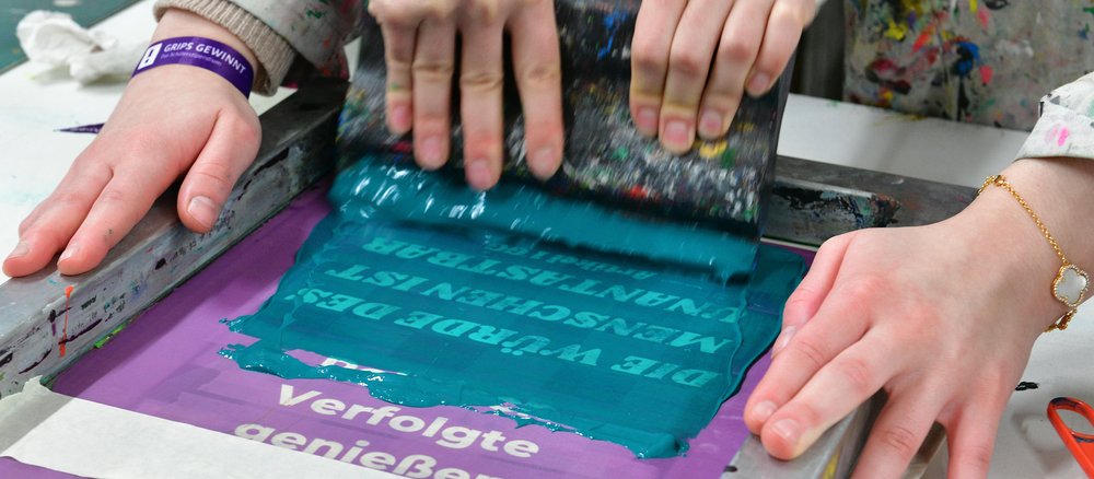 Zwei Hände die einen Beutel per Siebdruck bedrucken.