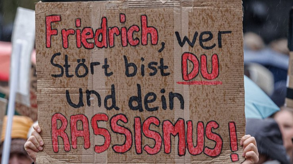 Demonstrationsschild mit Aufschrift “Friedrich, wer stört bist du und dein Rassismus!”