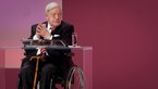 Helmut Schmidt in Rollstuhl auf Podium
