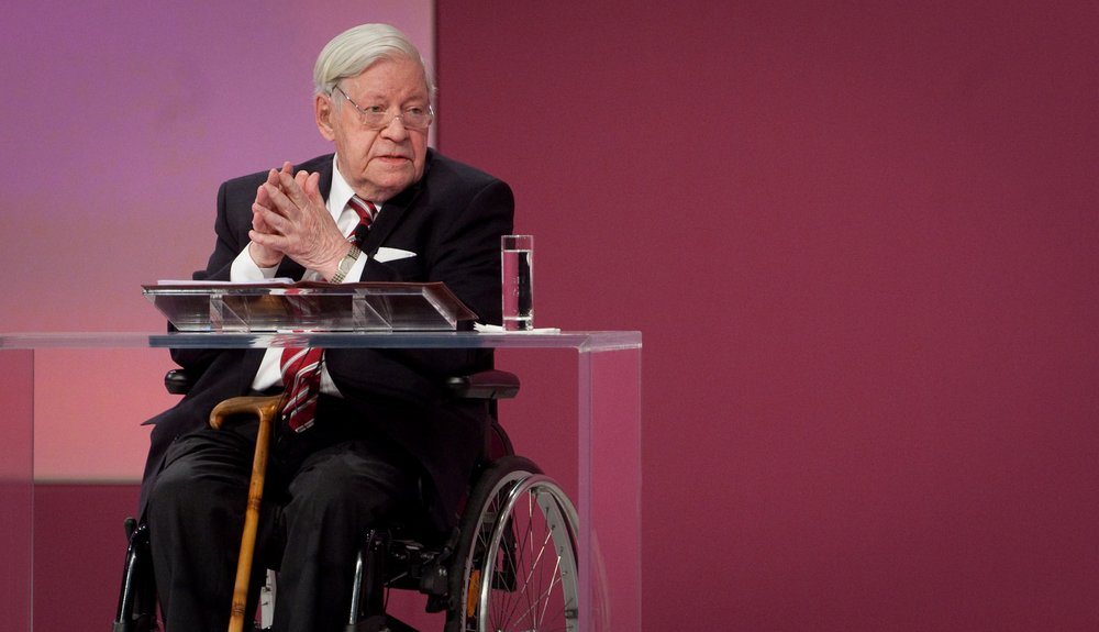 Helmut Schmidt in Rollstuhl auf Podium