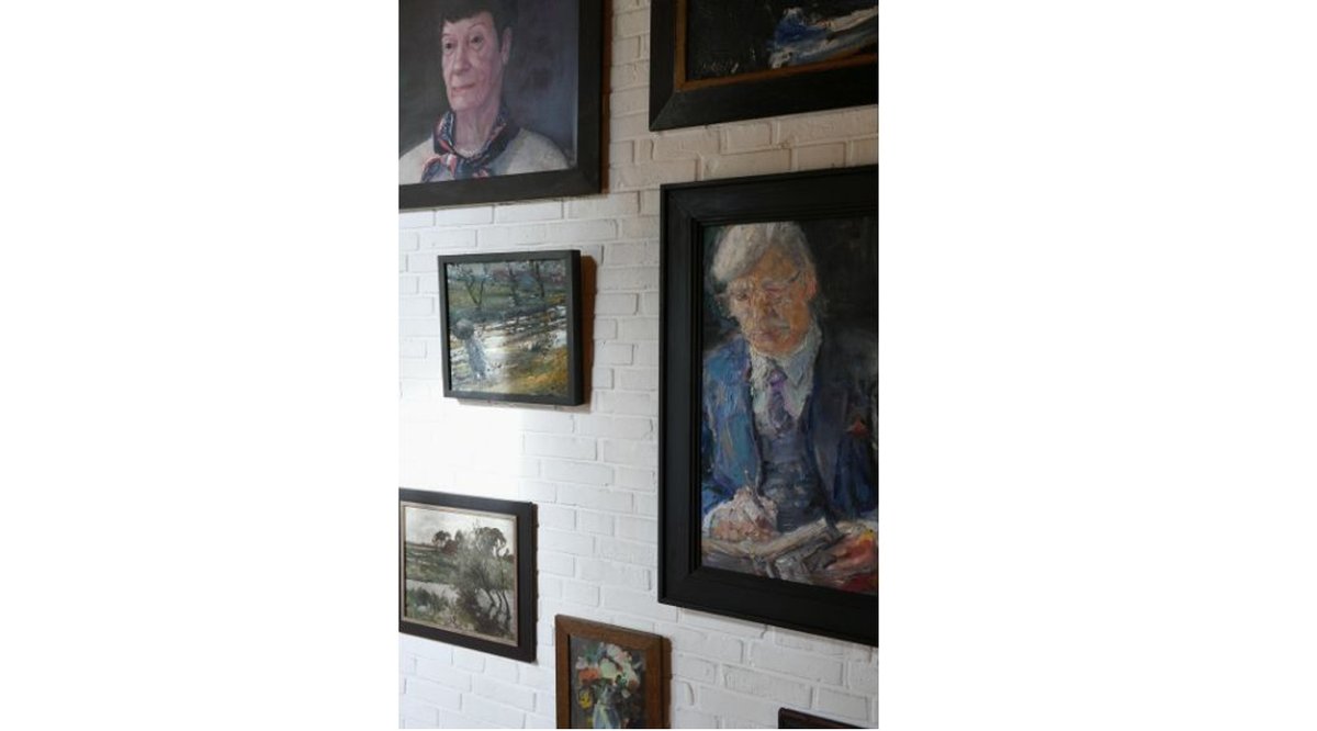 An der Wand im Wohnzimmer des Wohnhauses hängen einige Gemälde. Zu sehen sind unter anderem Portraits von Helmut und Loki Schmidt zu sehen.