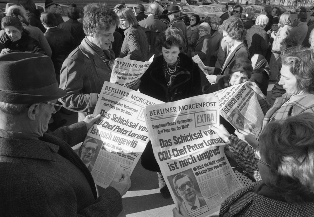 Black and white photo of several people reading the Berliner Morgenpost