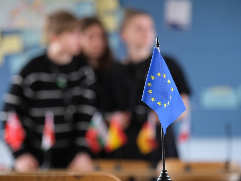 EU flag in the foreground and pupils blurred in the background