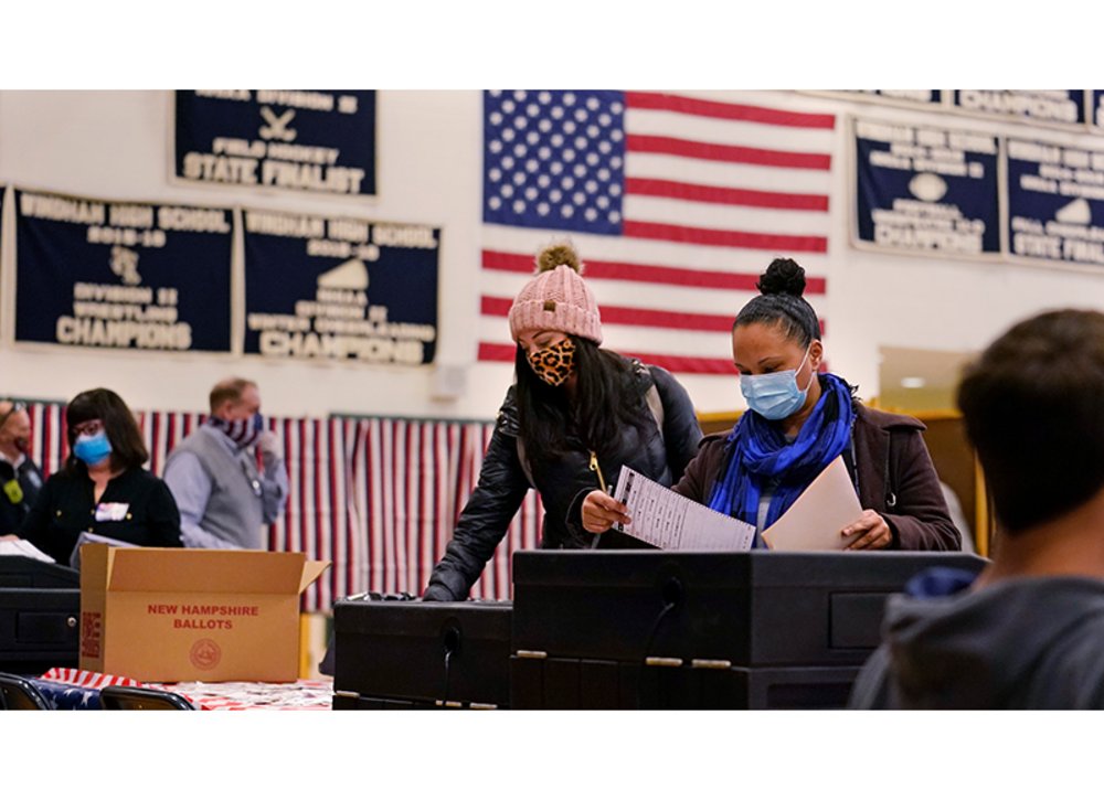 Wahllokal in Amerika, Personen mit Atemschutzmasken stehen an Wahlurnen