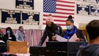 Wahllokal in Amerika, Personen mit Atemschutzmasken stehen an Wahlurnen