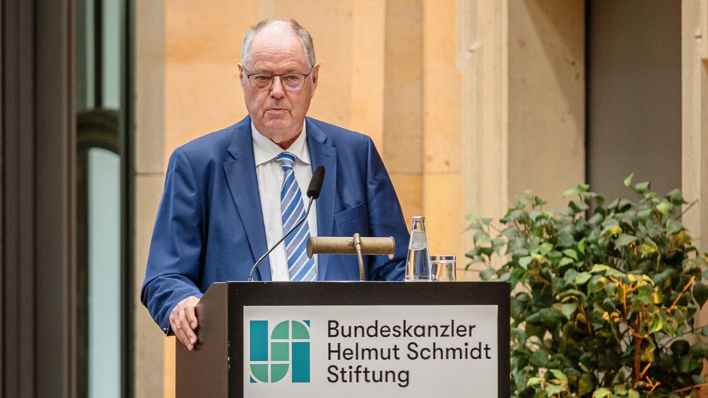 Colour photograph: Peer Steinbrück is standing on a stage and greeting the audience