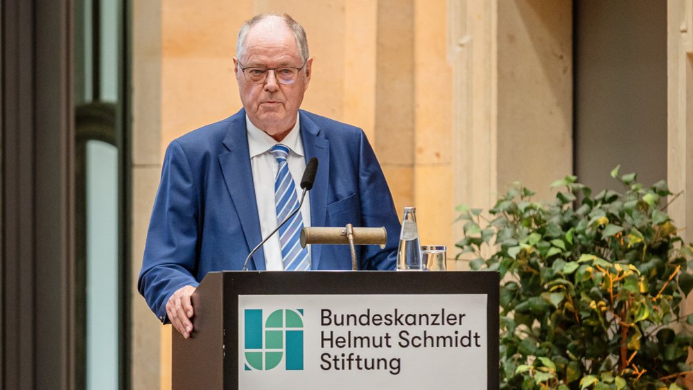 Farbfoto: Peer Steinbrück steht auf einer Bühne und begrüßt das Publikum