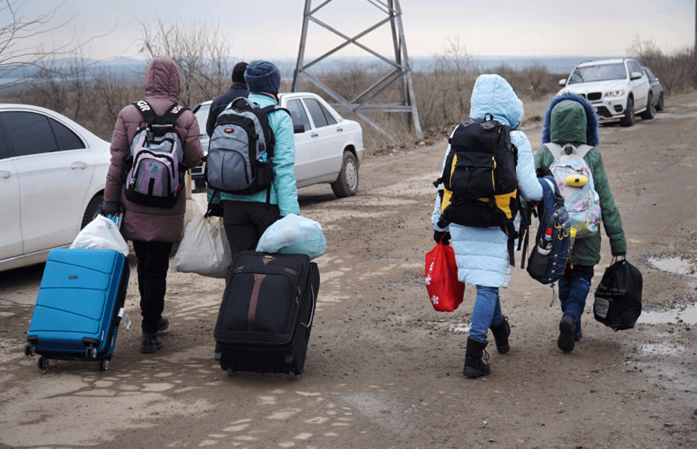 Ukrainian refugees with suitcases and rucksacks from behind