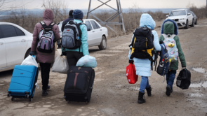 Ukrainian refugees with rucksacks and suitcases from behind
