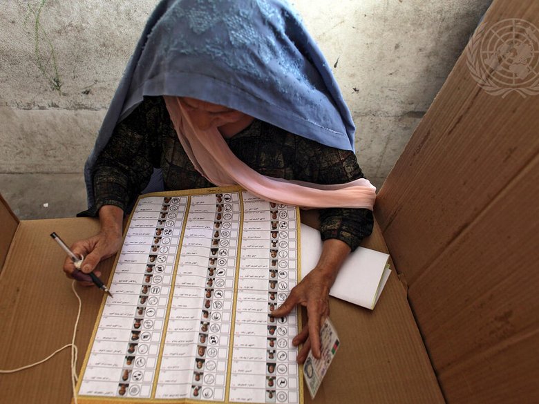 Elderly Afghan woman filling in a ballot paper