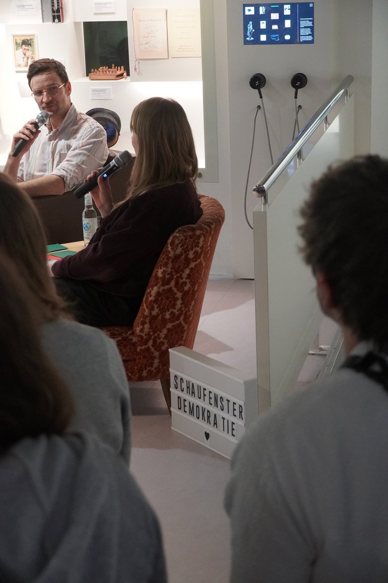Ein Ausschnitt aus der Veranstaltung Schaufenster Demokratie. Eine Person spricht mit Mikrofon.