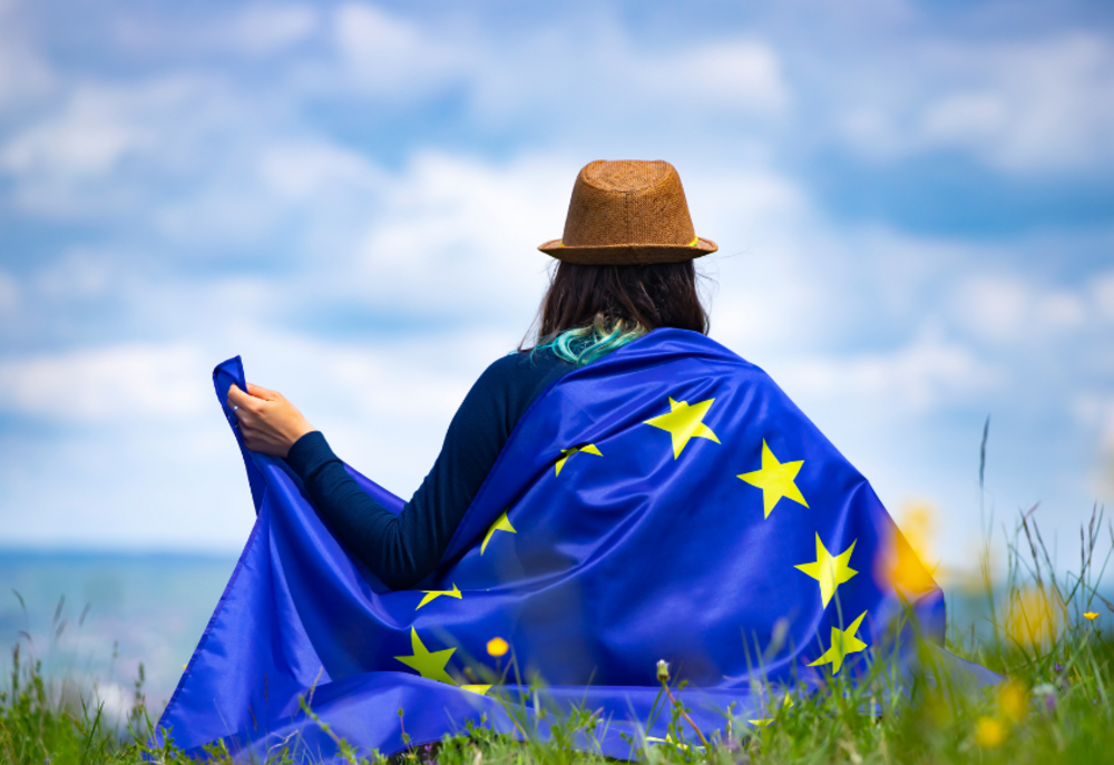A person photographed from behind with the EU flag around their shoulders.